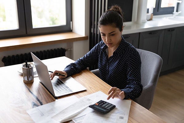 Mujer en escritorio con computador y calculadora en escritorio
