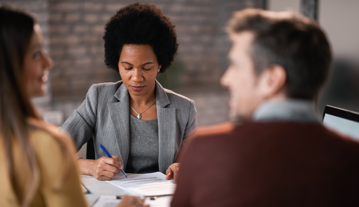 Woman in gray jacket writing on desk