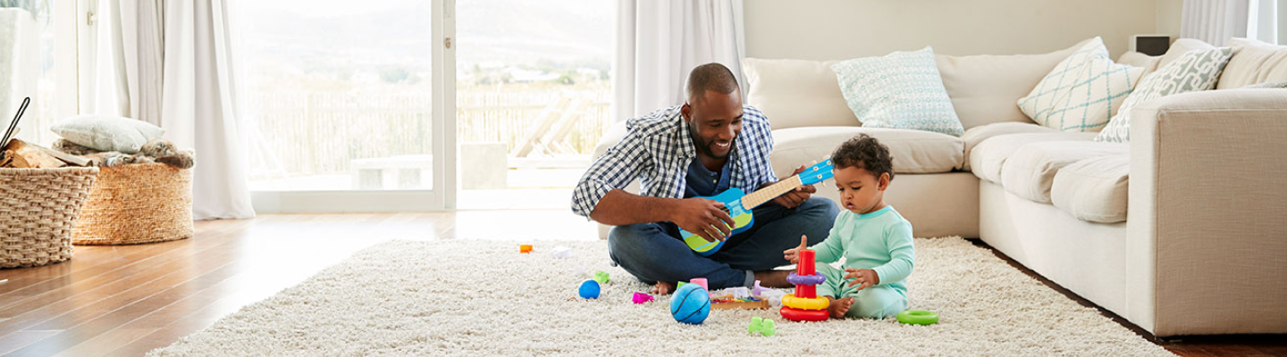 Hombre jugando con su hijo en el piso de la sala
