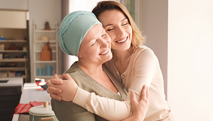 Mujer sosteniendo un paciente de cáncer con un turbante de quimioterapia azul claro.