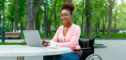 Woman in a wheelchair with her laptop and a cup of coffee