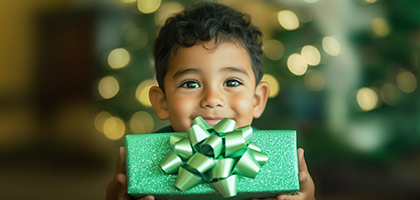 niño  sosteniendo un regalo muy feliz